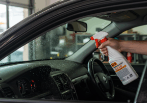 A person cleans the interior of a car with a spray, illustrating tips for effective car detailing.