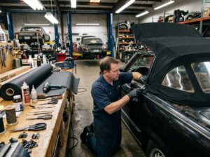Auto specialist inspecting and repairing convertible soft top frame in workshop